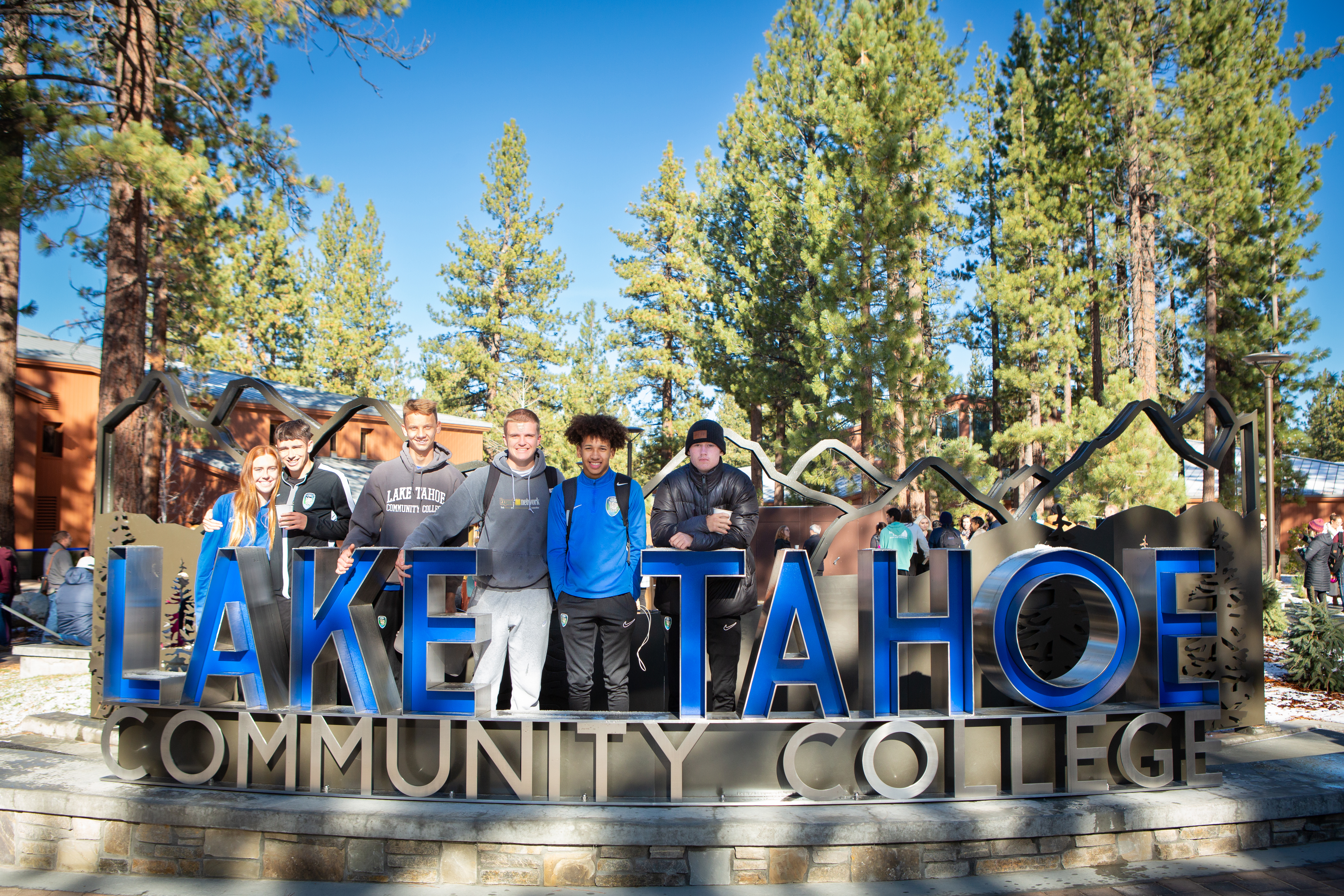 Students standing behind the new Main Building entrance and plaza sign