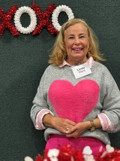 A European-American woman with blonde hair holding a red heart.