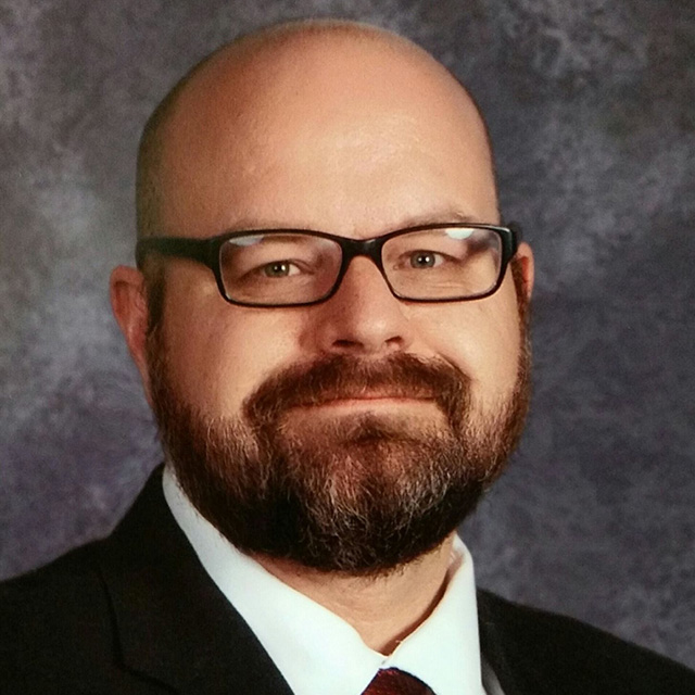 Headshot of a bald European-American man with glasses.
