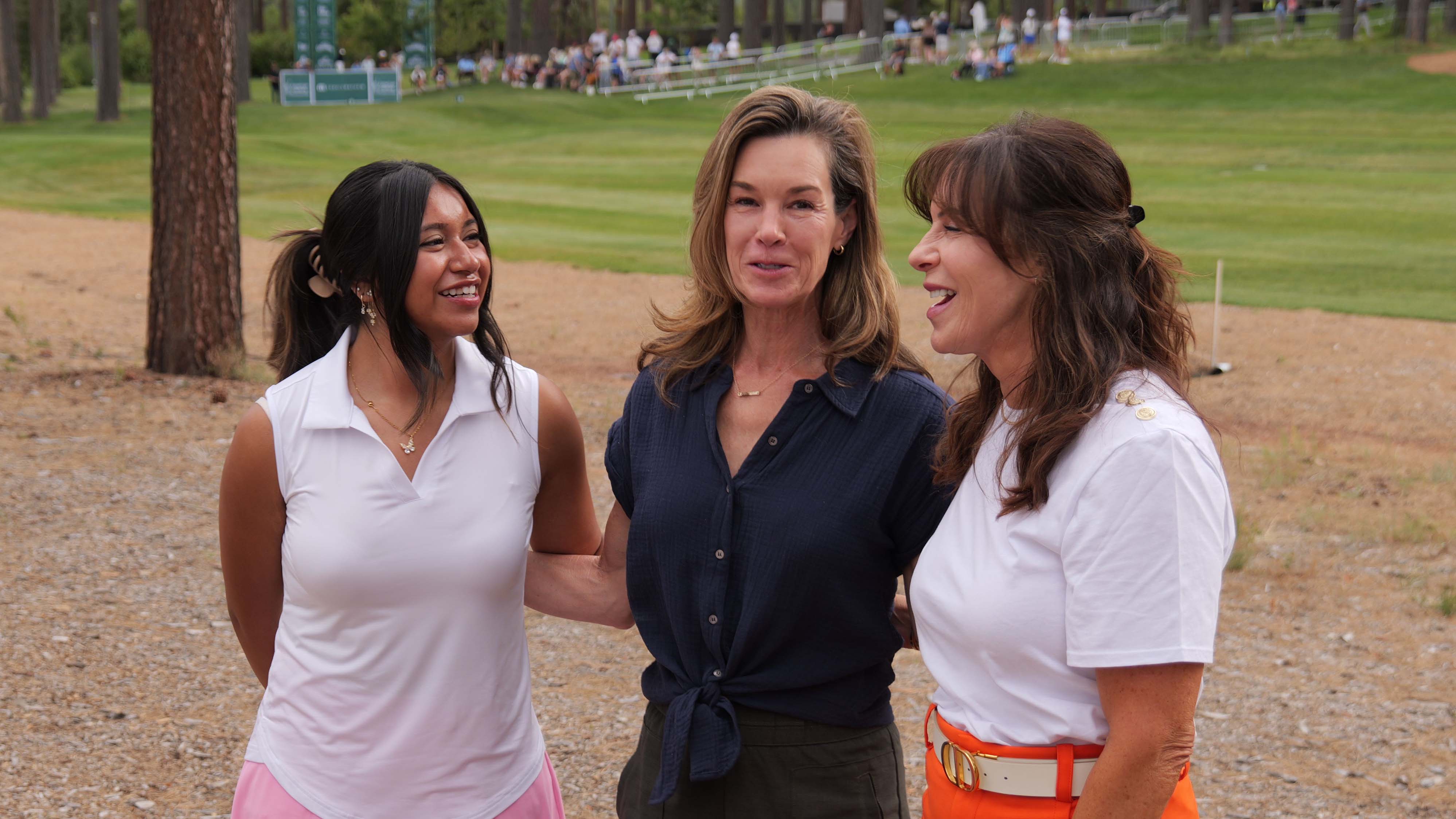 26_valery_acc_scholarship_05 On the left, a young woman in a sleeveless white top smiles, while the woman in the center wearing a navy blue top looks toward the camera, and the woman on the right in a white top and orange pants laughs.