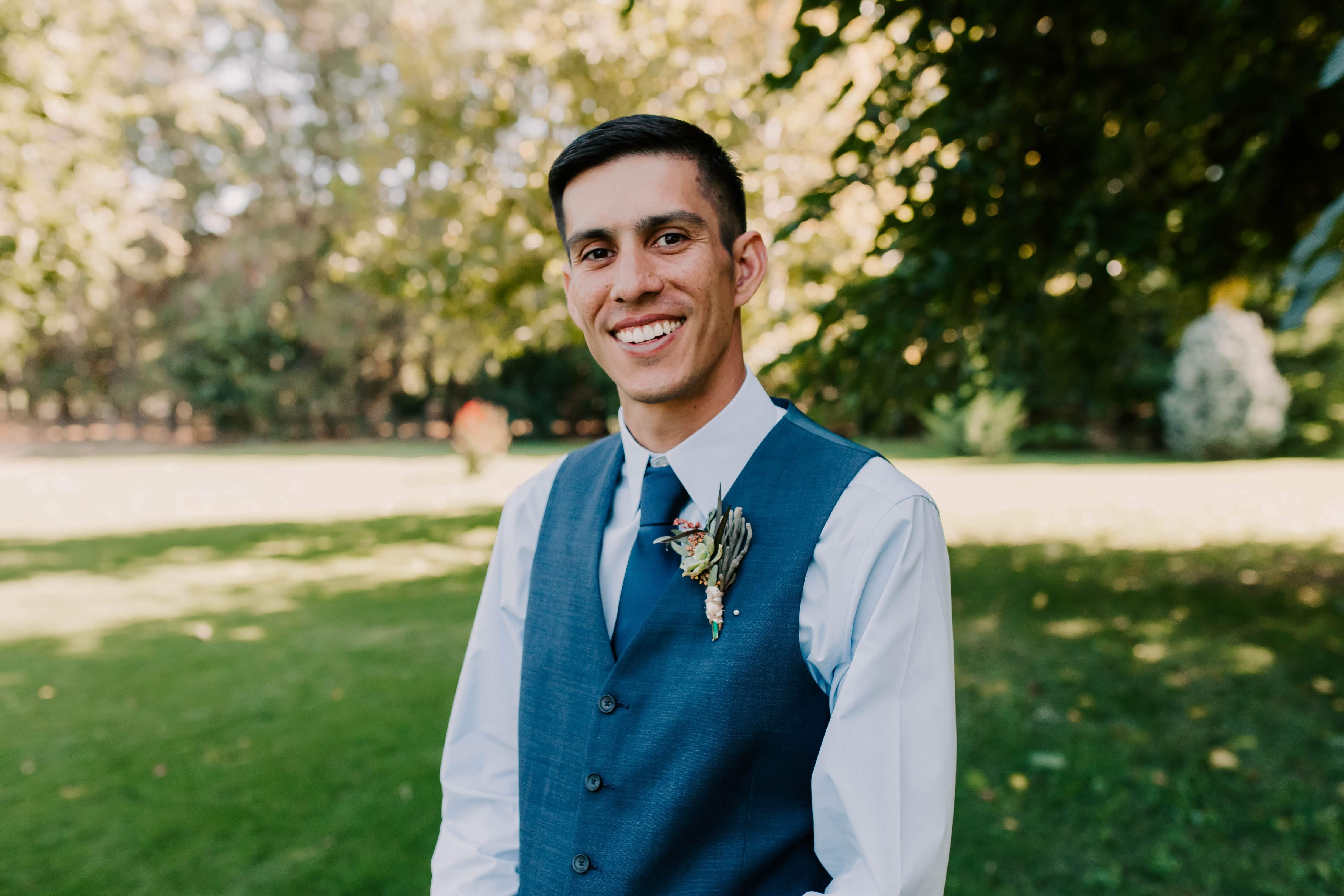 A European-American man with a white dress shirt and a blue vest.