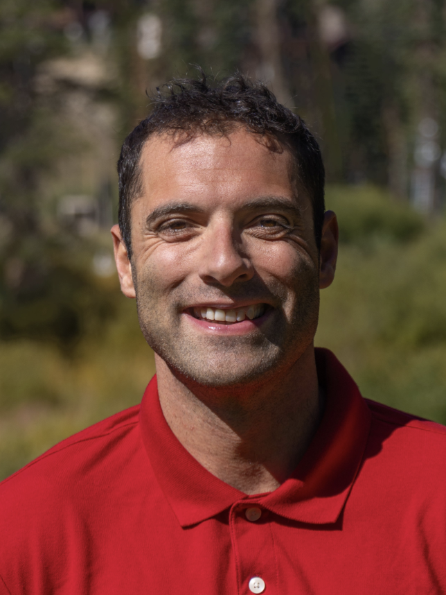 A European-American man wearing a red polo shirt.