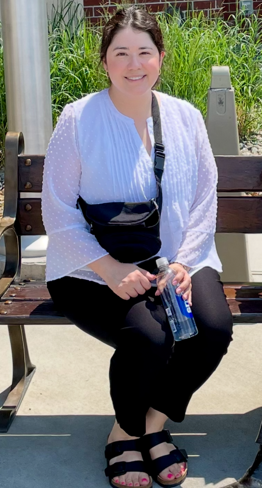 An Hispanic woman wearing a white blouse and black pants.